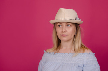 Fashion pretty young woman wearing a straw hat and blue dress isolated on pink background. Beautiful women, lifestyle portrait. Summer vacation, holidays concept. Copy space