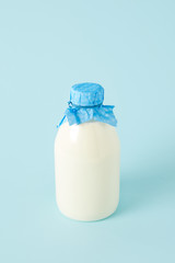 closeup shot of fresh milk in bottle wrapped by paper on blue background