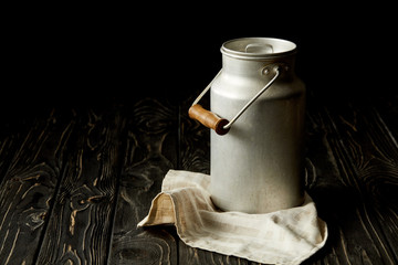 milk in aluminium can on sackcloth on black background