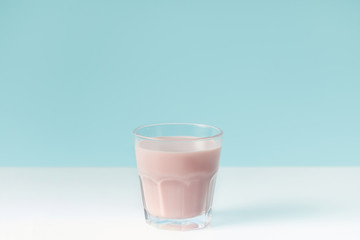 closeup view of strawberry milkshake in glass on blue background