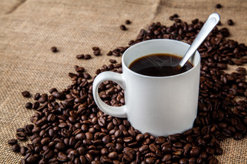 White coffee mug with coffee beans on hessian sack cloth