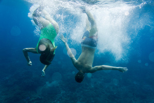 underwater photo of couple diving together in ocean
