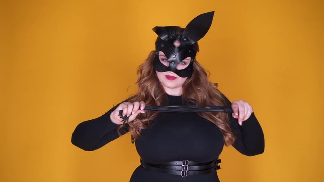 Sexy plump girl in leather bunny mask holding whip