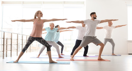 Group of people in sportswear practicing yoga indoors