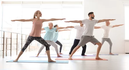  Group of people in sportswear practicing yoga indoors © New Africa