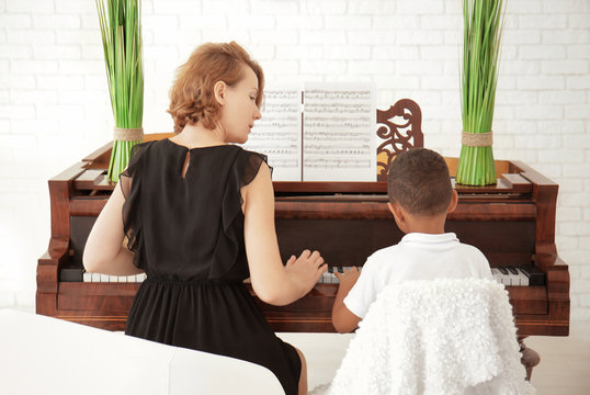 African-American boy with teacher learning to play piano indoors