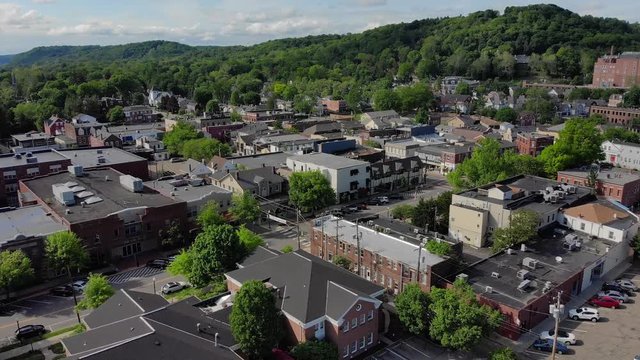 SEWICKELY, PA - Circa May, 2018 - A daytime forward wide aerial establishing shot of a small town's business district on a sunny summer day. Pittsburgh suburbs.  	