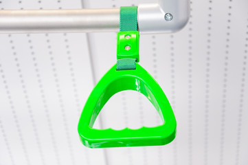 Green hanging handhold for standing passengers in a modern train