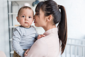 young beautiful mother and little child embracing at home
