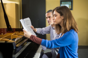 Young womanl having piano class with her teacher.