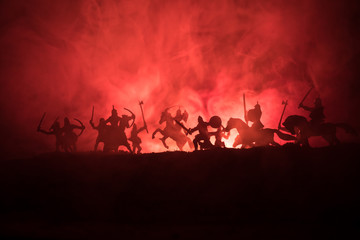 Fototapeta na wymiar Medieval battle scene with cavalry and infantry. Silhouettes of figures as separate objects, fight between warriors on dark toned foggy background. Night scene.