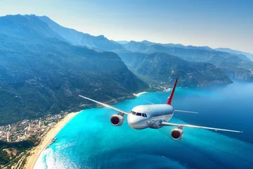 Fotobehang Vliegtuig Vliegtuig vliegt over verbazingwekkende bergen met bos en zee bij zonsopgang in de zomer. Landschap met wit passagiersvliegtuig, lucht, eilanden en blauw water. Passagiersvliegtuigen. Reizen en toevlucht. Toerisme