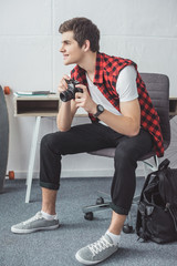 smiling teenager with film camera sitting at home