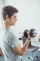 Fototapeta na wymiar young teenager exercising with dumbbell at home
