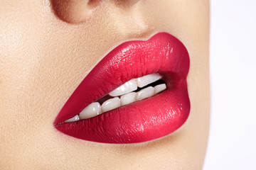 Close-up macro shot of female mouth. Sexy Glamour red lips Makeup with sensuality gesture. Magenta gloss lipstick