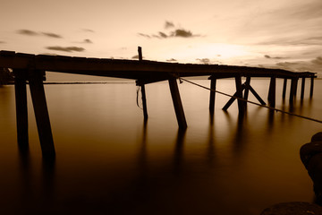 Wooden bridge in the evening sea using Long Exposure Photography technique to make vintage tone.