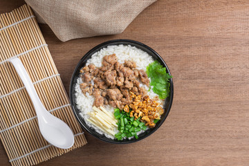 top view of boiled rice with pork and vegetable in a ceramic bowl on wooden table. homemade style food concept.