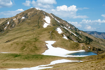 mountain covered by snow and lake under cloudy blue sky in Romania