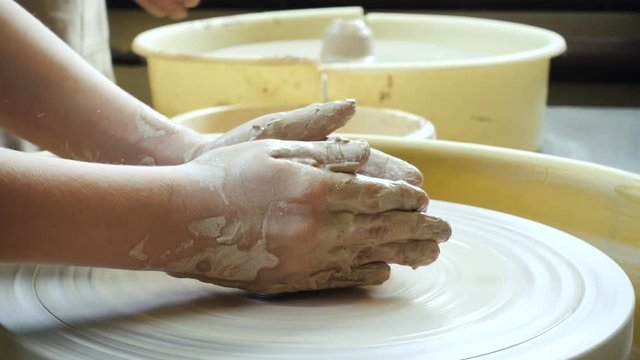 child hands making a clay pottery
