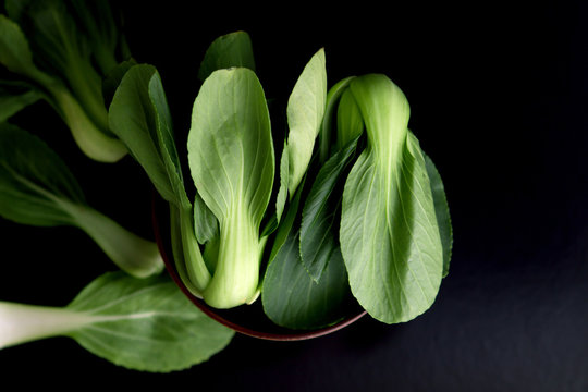 close up Fresh baby green bok choy in bowl on the  black background , overhead or top view shot