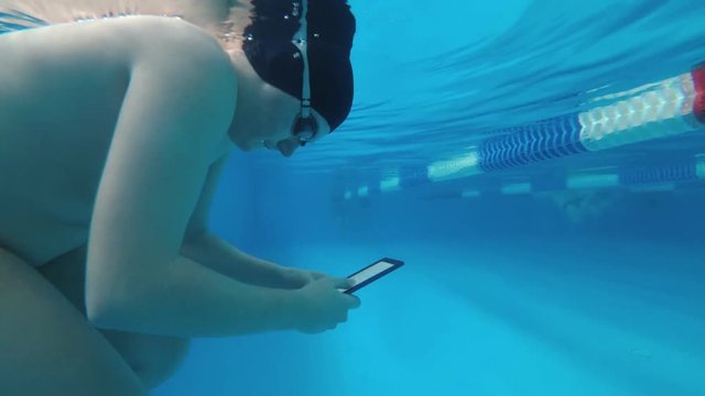 The guy is reading an electronic book underwater. This is a special waterproof electronic device. You can read the text and show signs directly underwater.