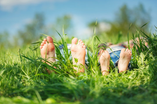 Adult's and child's bare feet on green summer grass