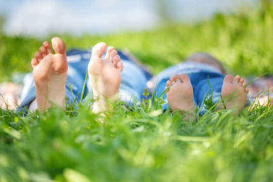 Adult's and child's bare feet on green summer grass