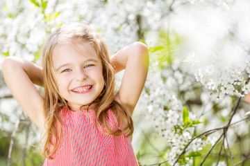 Happy little girl playing in spring cherry garden