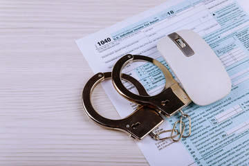 Police handcuffs lie on the tax form 1040. The concept of problems with the law in the aftermath of...