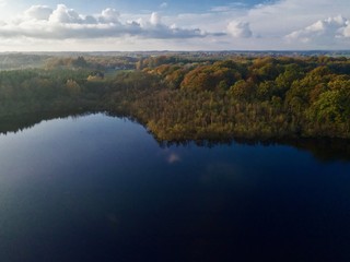 Fototapeta premium Aerial view over lake in Sweden with forest around with shade of brown and orange