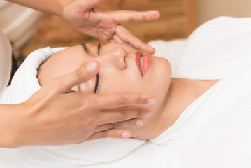 Face massage. Spa skin and body care. Close-up of young woman getting spa massage treatment at beauty spa salon. Facial beauty treatment.