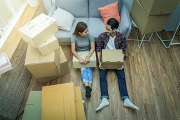 Top view Asian young couple sitting for relax after successfull packing the cardboard box for moving in new house, Moving and House Hunting concept