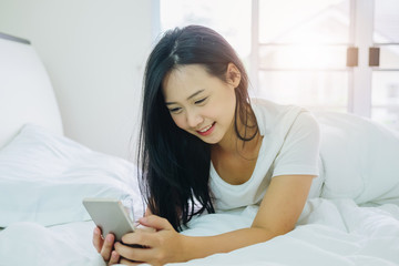 Cute girl using smartphone for online shopping or call phone on the bedroom in house.