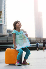 Child with suitcase and city map on summer vacation. Travel and adventure concept.