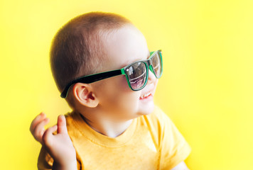 baby boy in sunglasses on yellow background