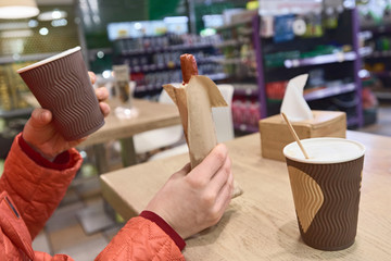 Woman's hands holding cup of coffee and hot dog