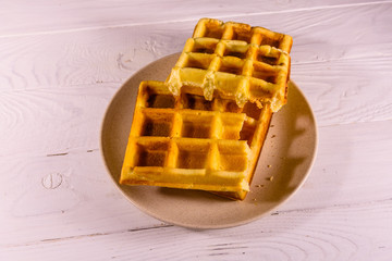 Ceramic plate with belgian waffles on wooden table