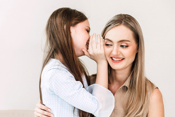 Obraz na płótnie Canvas Little daughter whispers secret to her mother's ear