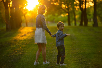 Fototapeta premium Mother and little son in park or forest, outdoors. Hugging and having fun together
