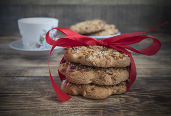 Cookie with nut sprinkles are stacked and tied with a red ribbon. Delicious cookies on wooden background. Homemade cake. The nut cookie.