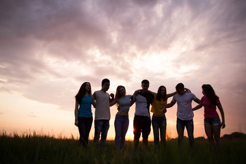 Silhouettes of people againstl sunset sky