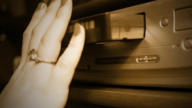 Removing a VHS Tape into VHS player - old retro color graded sepia concept ALT ANGLE