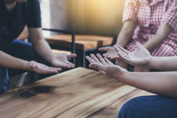 Christian bother and sister raise hands up and praying together around  wooden table ,small  prayer group in church, christian background with copy space for your text.