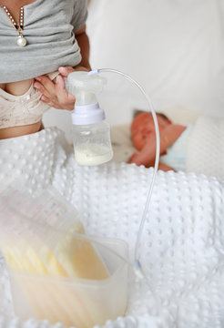 Automatic breast pump. Mothers breasts milk for newborn baby in bed room at home.
