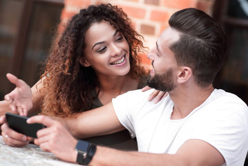 Obraz premium Happy loving couple using a smartphone sitting in terrace
