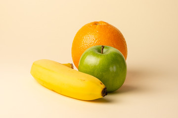Apple orange and banana isolated on yellow background