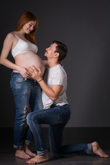 Husband and pregnant wife on gray background