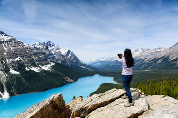 A Tourist woman taking picture of Peyto Lake with mobile phone, Banff National Park