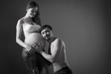 Husband and pregnant wife on gray background