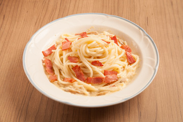 Spaghetti with bacon and cream sauce on plate.